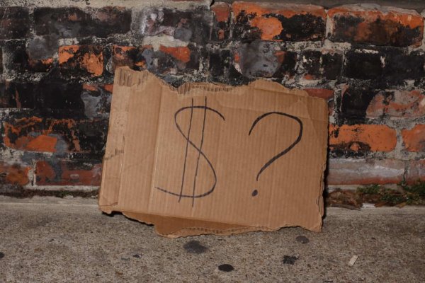 cardboard sign with a dollar and question mark symbols