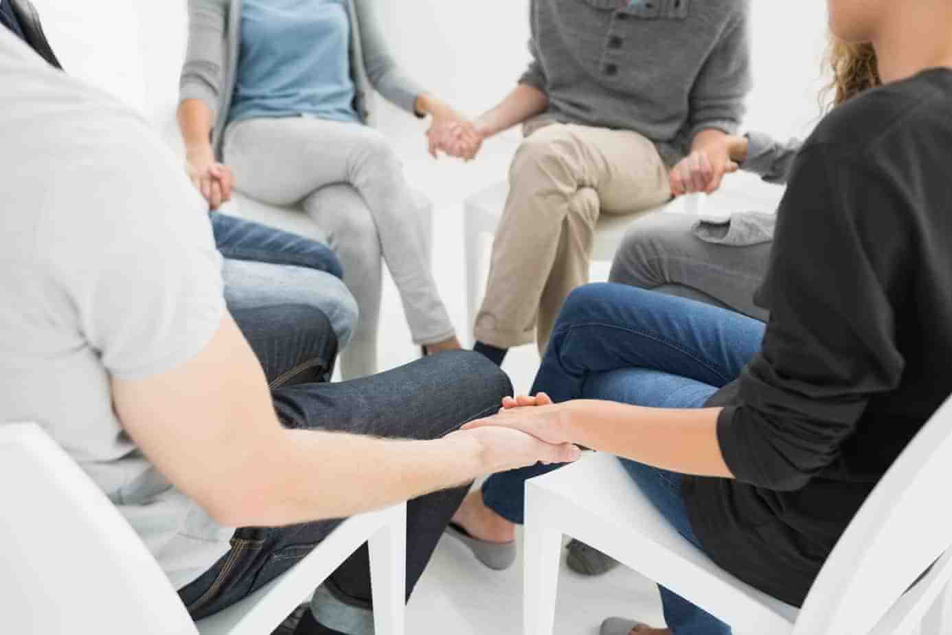 Group therapy in session sitting in a circle with therapist suicide survivor loss group therapy