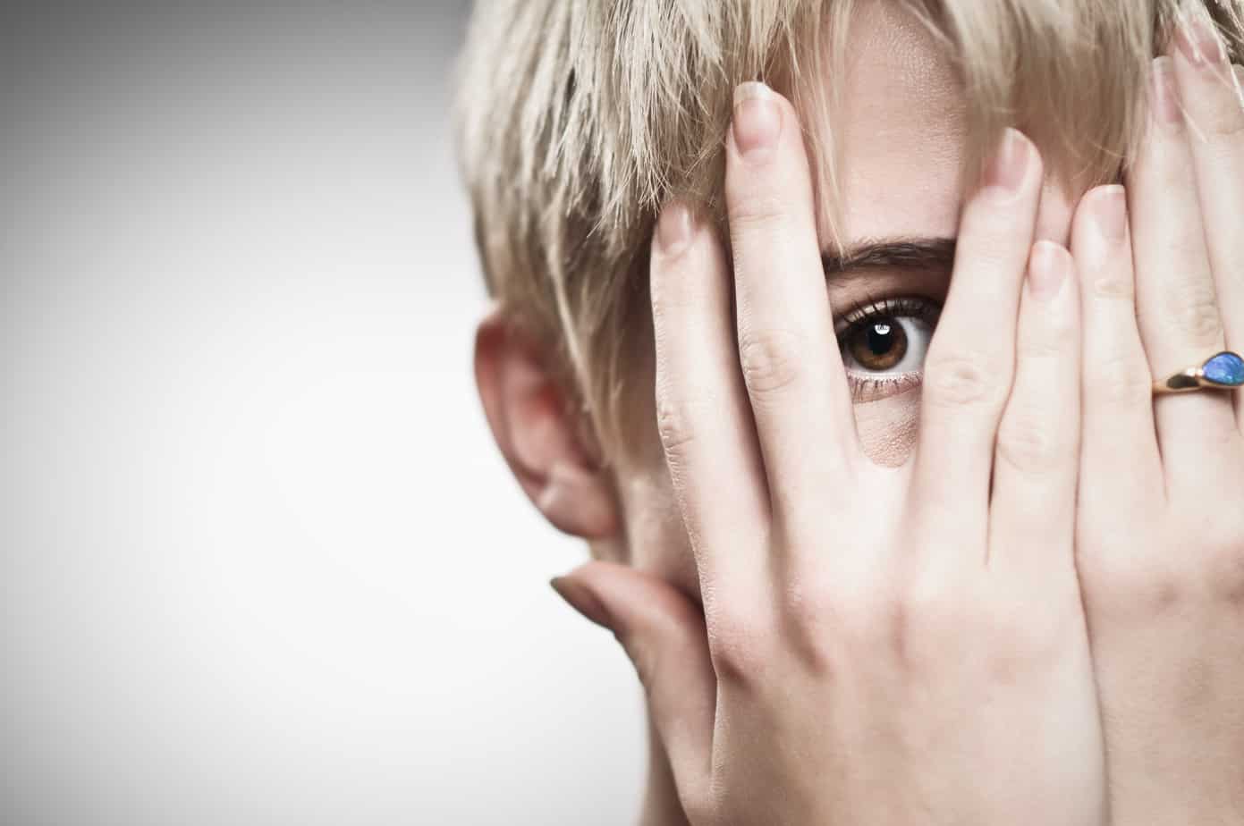 Beautiful Young Caucasian Woman Peeking Through Fingers caucasian woman covering her face in shame